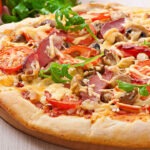 Carbonara pizza topped with creamy sauce, bacon, eggs, and mozzarella cheese, served on a crispy thin crust.