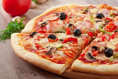 Capricciosa pizza with ham, mushrooms, olives, artichokes, and mozzarella cheese, served on a crispy thin crust.